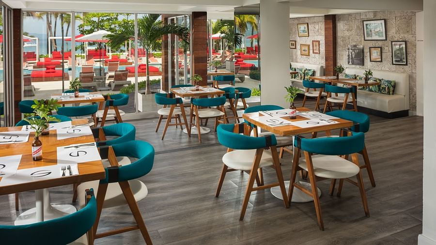 A stylish cafe by the pool with cushioned chairs placed around wooden tables - S Hotel Montego Bay, Jamaica