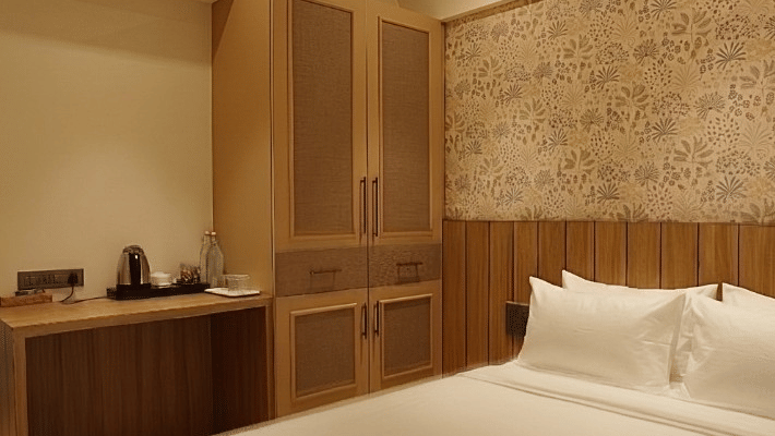 A queen size bed, a wardrobe, and a desk at Bougainvillea, Alibaug.