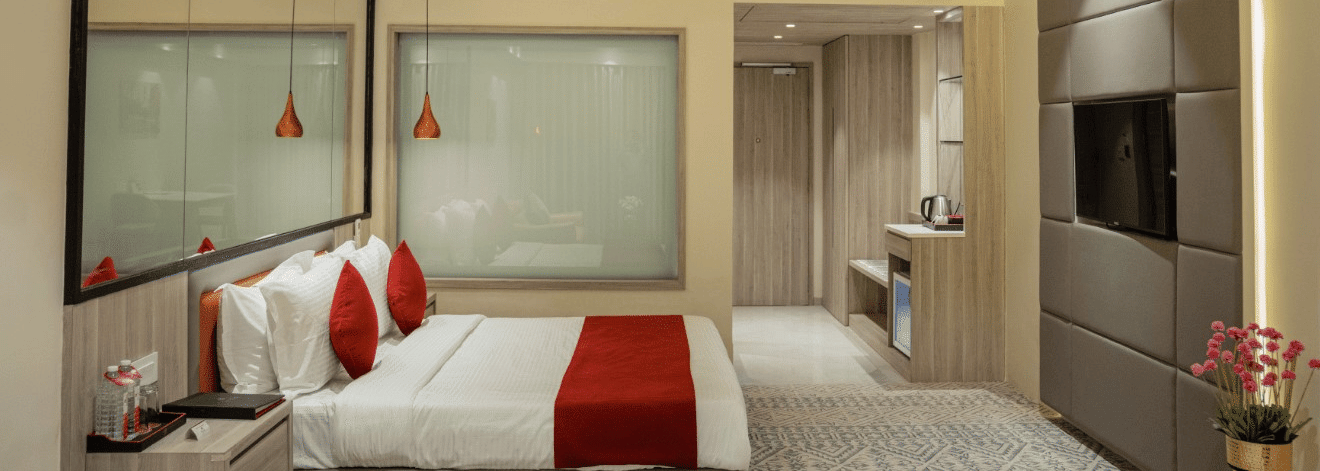 A neat, modern hotel room with a bed, TV, and a large mirror.