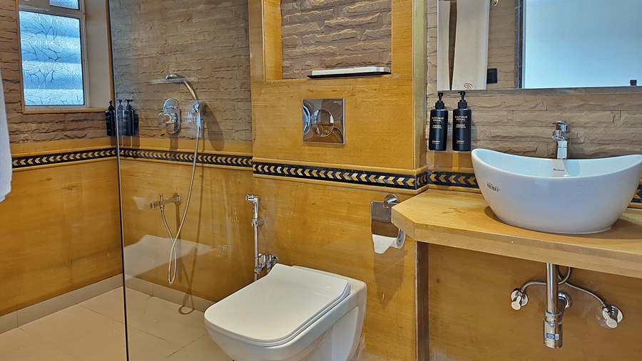 Bathroom with a toilet, washbasin, glass shower enclosure, and tiled walls.