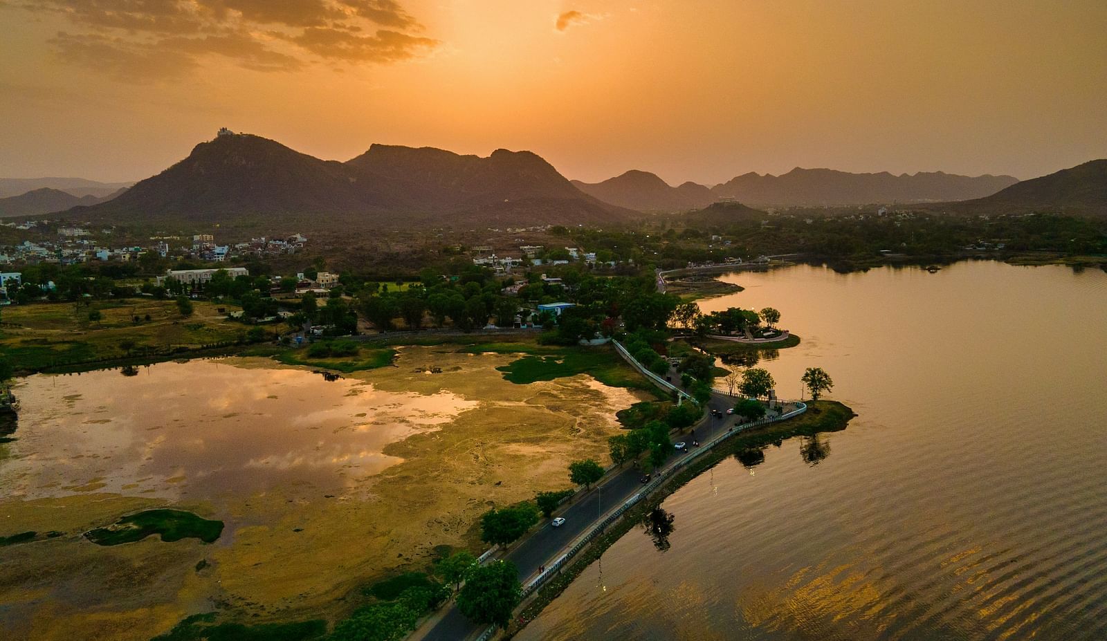 An overview of Fateh Sagar Lake with the sun setting in the background over the mountains