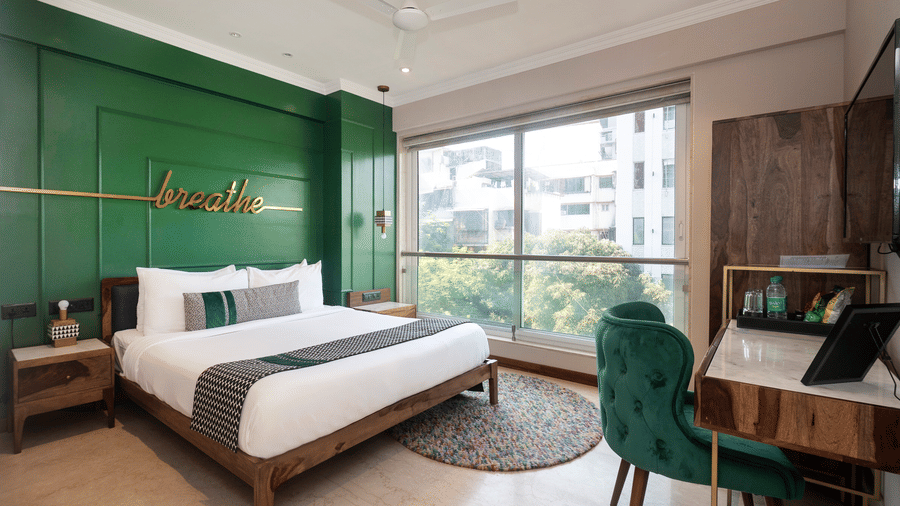 Deluxe Room featuring a plush bed facing the wall-mounted TV with a work desk below, offering a serene stay in Bandra at Theory9 - Premium Service Apartments