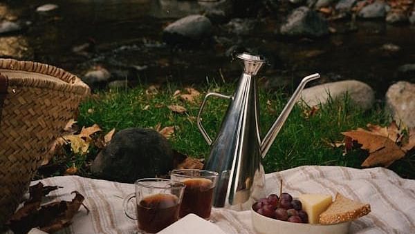Image of a picnic layout with various food by the river | Faraway Cottages, Auli