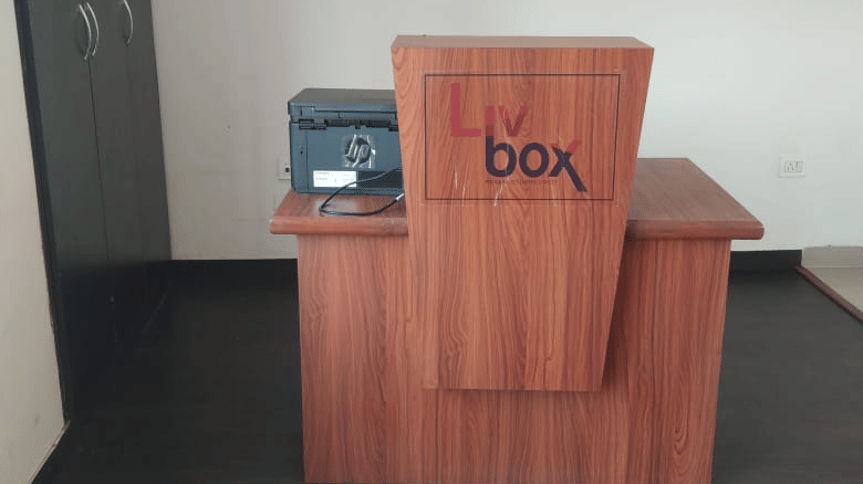 Wooden reception counter with Livbox branding and a small safe at Livbox, Rudrapur.