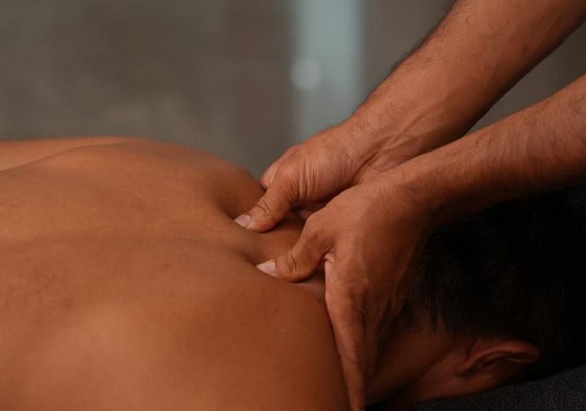 A masseuse applying pressure on the neck of a client during acupressure - Shreyas Retreat