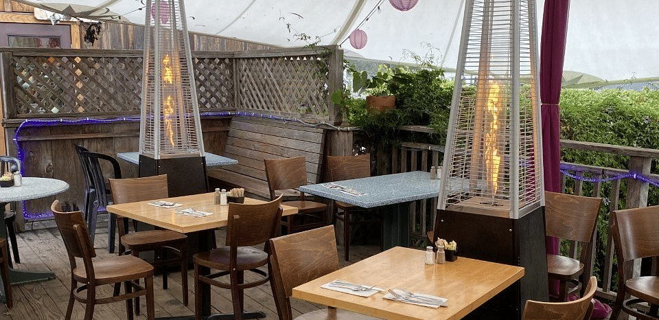 An outdoor patio with tables and chairs under a tent-like structure.