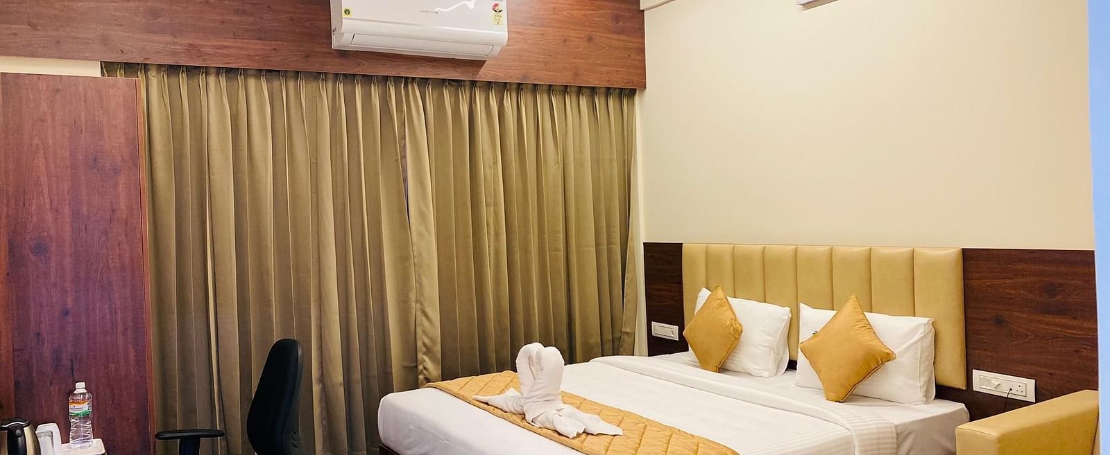 Warm, inviting bedroom with elegant curtain backdrop and work desk at Hotel Sahara Tree.