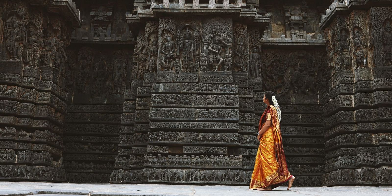 image of a woman dressed in a yellow saree walking in front of a temple