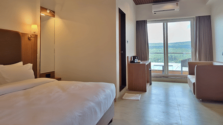 Bedroom with a double bed, padded headboard, seating, and balcony access