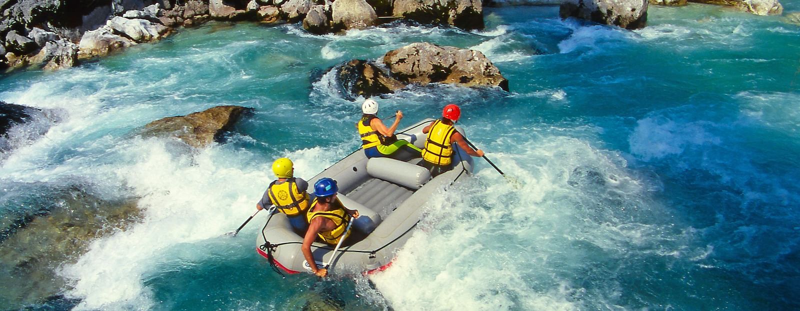 Group of adventurers river rafting through strong water currents.