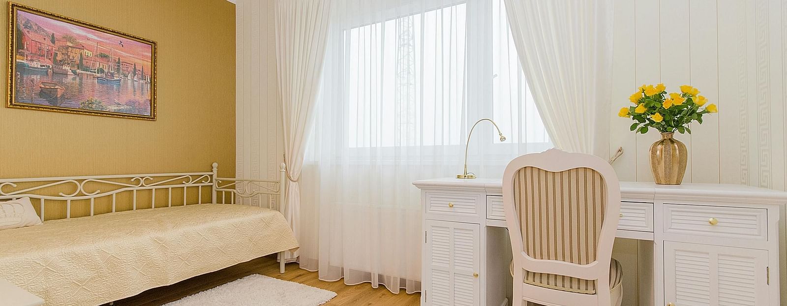 A well lit hotel room with a comfortable sofa and a desk with a chair