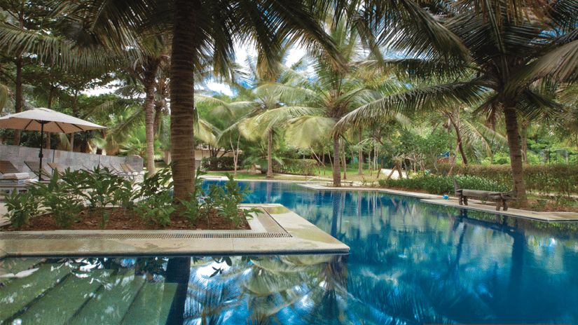 A pool surrounded by greenery at The Serai Kabini with a pool deck