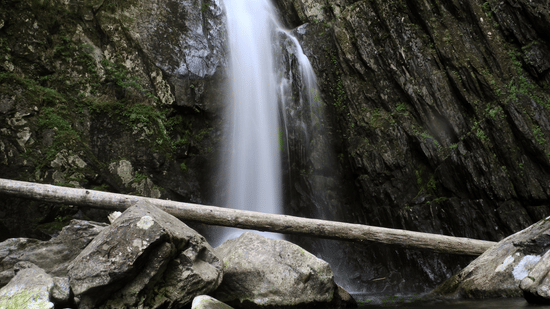 Small waterfall in between rocks flowing down to a pool of water.