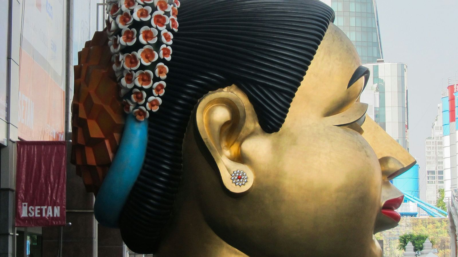 A close up shot of a golden bust of a women with the side of the face in view.