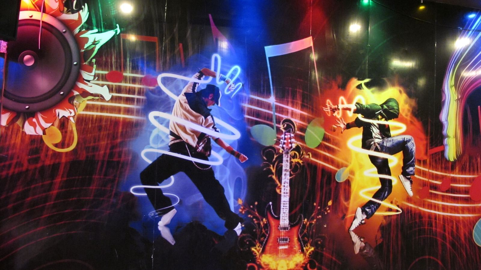 A close-up view of the wall mural, showcasing energetic dancers and dynamic light effects - TGI Apple Inn, Jaipur 