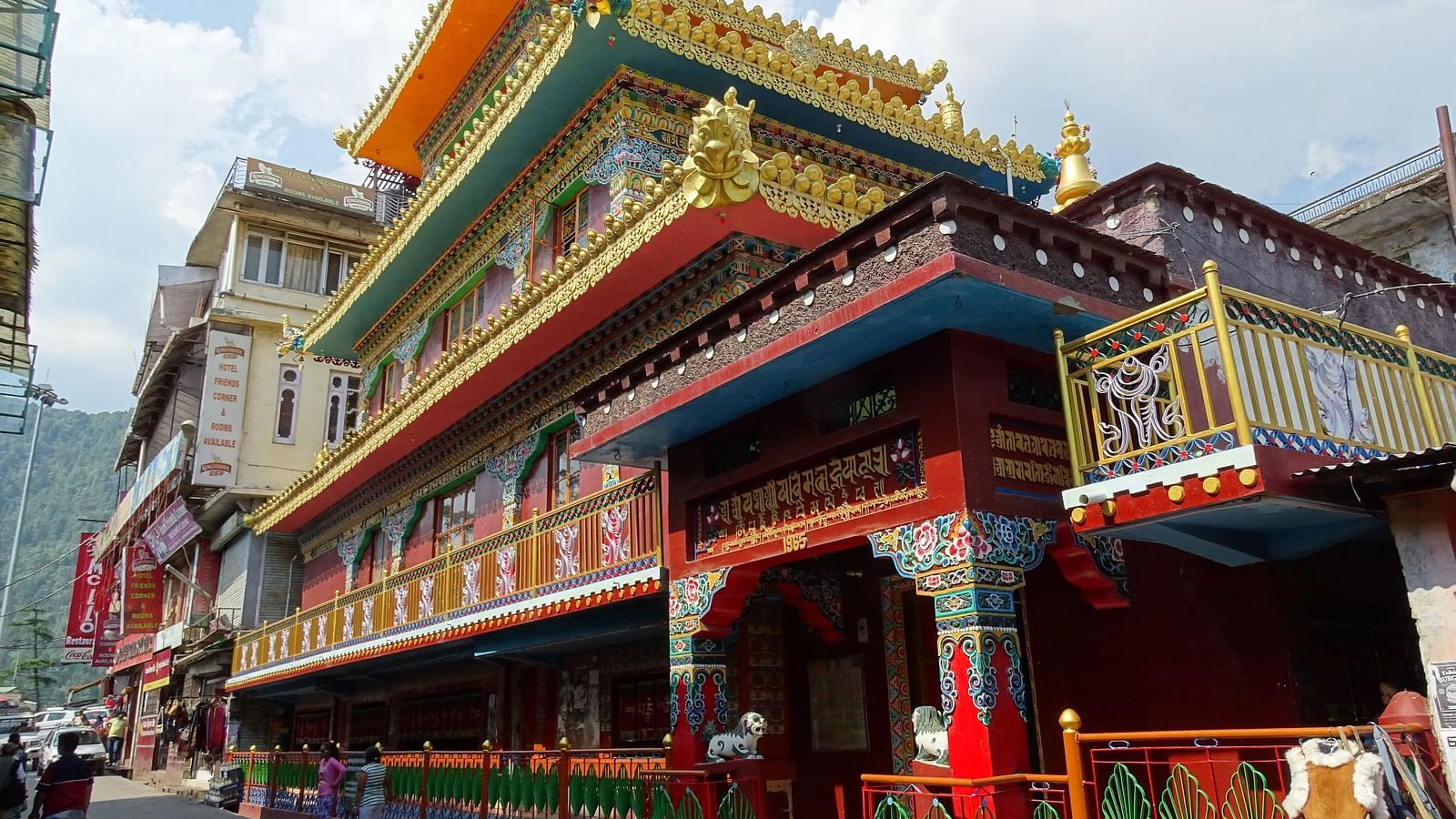 An image of a monastery near a road where people are seen walking
