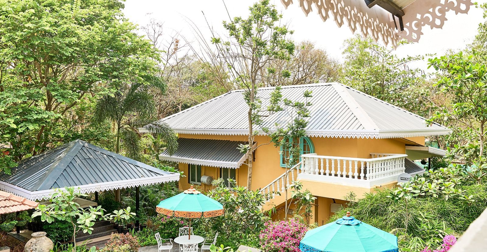 Facade view of Mayfair Manor, Alibag, with trees and plants surrounding the area
