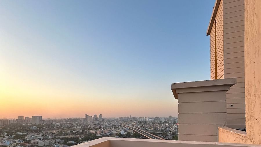 A view of the sunset from the balcony  with a potted plant at Rhythm Gurugram