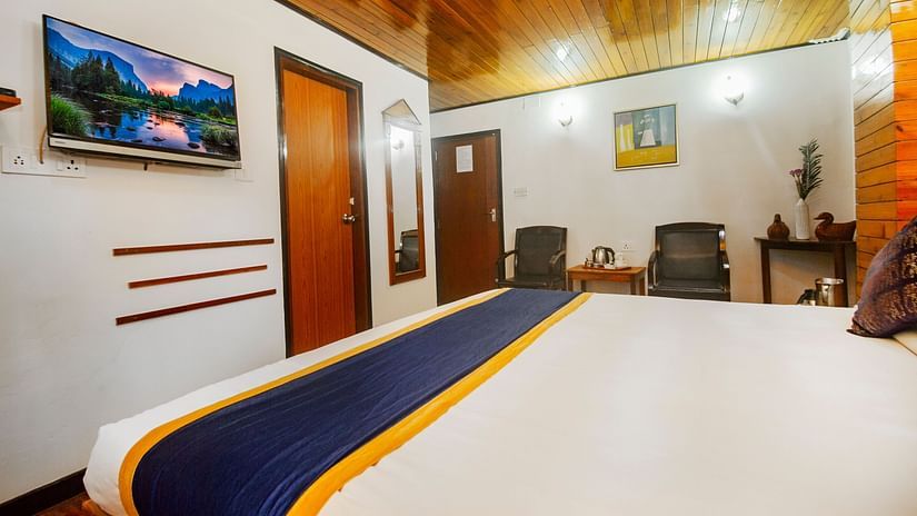 An image of a bedroom featuring a bed, chairs, a table with tea and coffee maker, and a mirror attached on the wall at Central Hill Resort, Gangtok