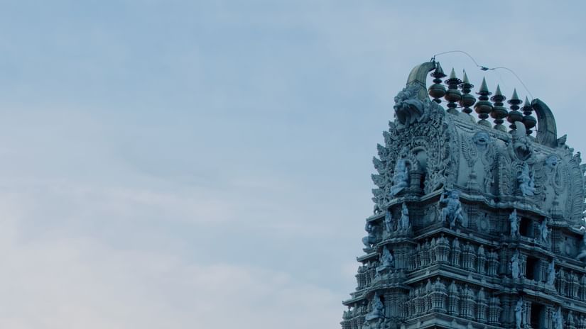 a view from below of a temple with intricate architecture on the exterior and blue sky in the background.