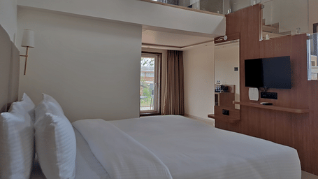 Bedroom with a double bed, television, wooden furnishings, and loft area
