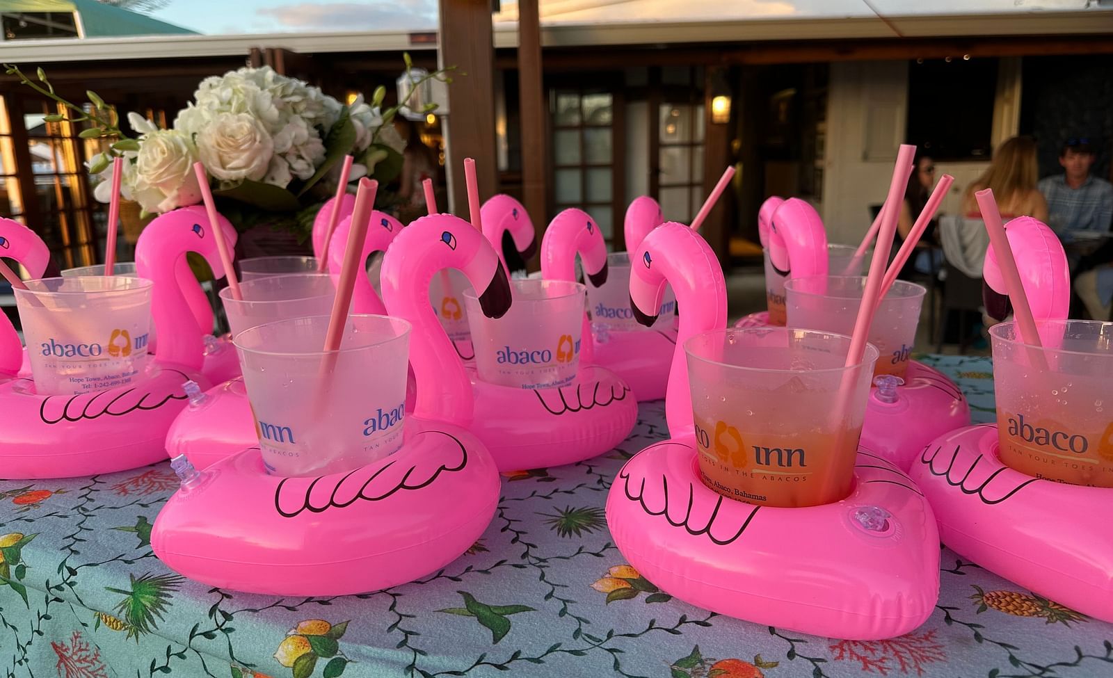 A table at the outdoor featuring small water balloons shaped as ducks where glasses with straws are kept. The glasses have Abaco Inn text written on them.