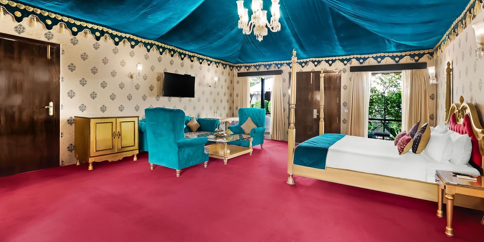 An overview of a tent with a double bed, chairs, a coffee table and a chandelier - Rajasthali Resort & Spa, Jaipur.