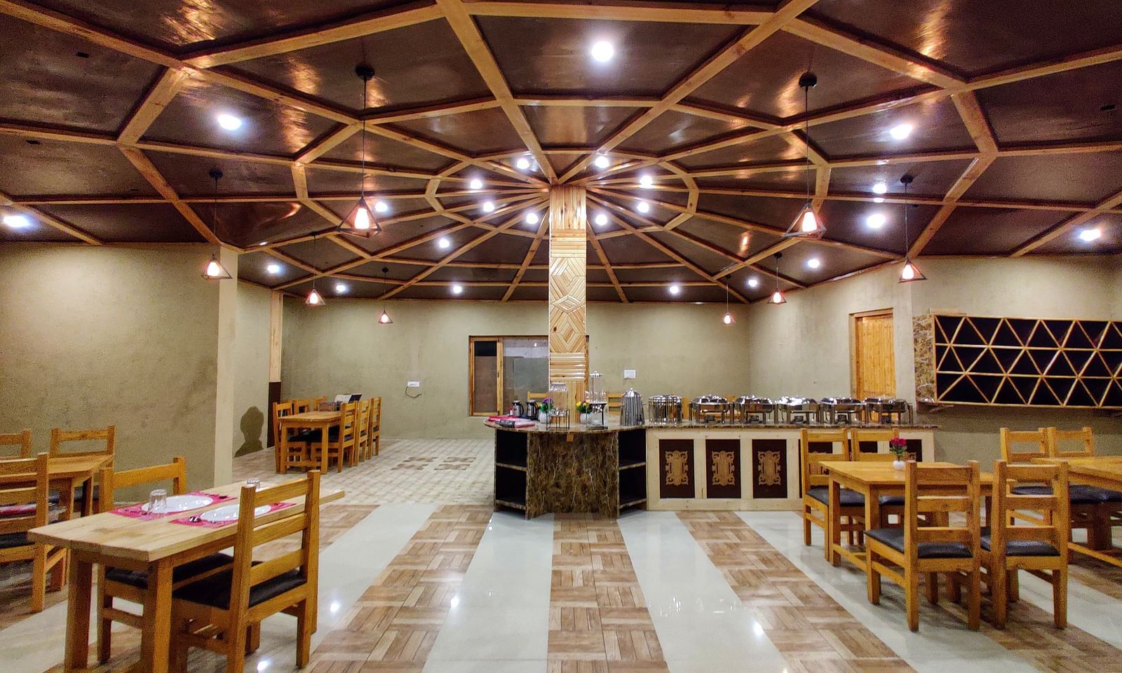 The interior of a dining area with wooden tables and chairs at White Sands Resort, Ladakh.