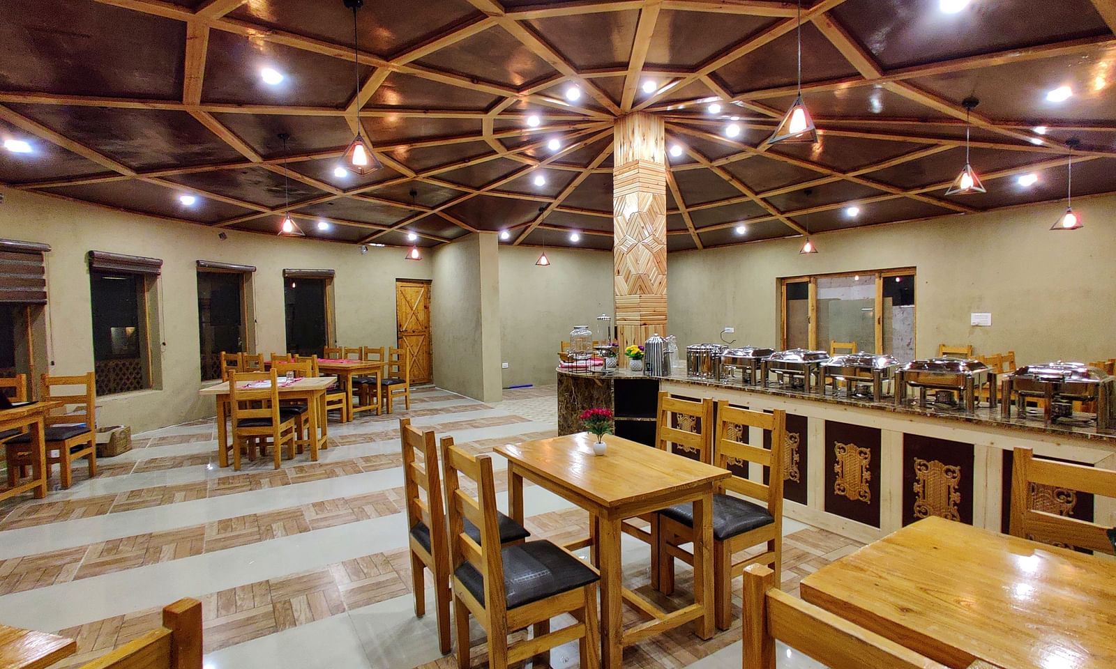 The interior of a dining area at White Sands Resort, Ladakh highlighting the wooden furniture, ceiling design, and buffet area.
