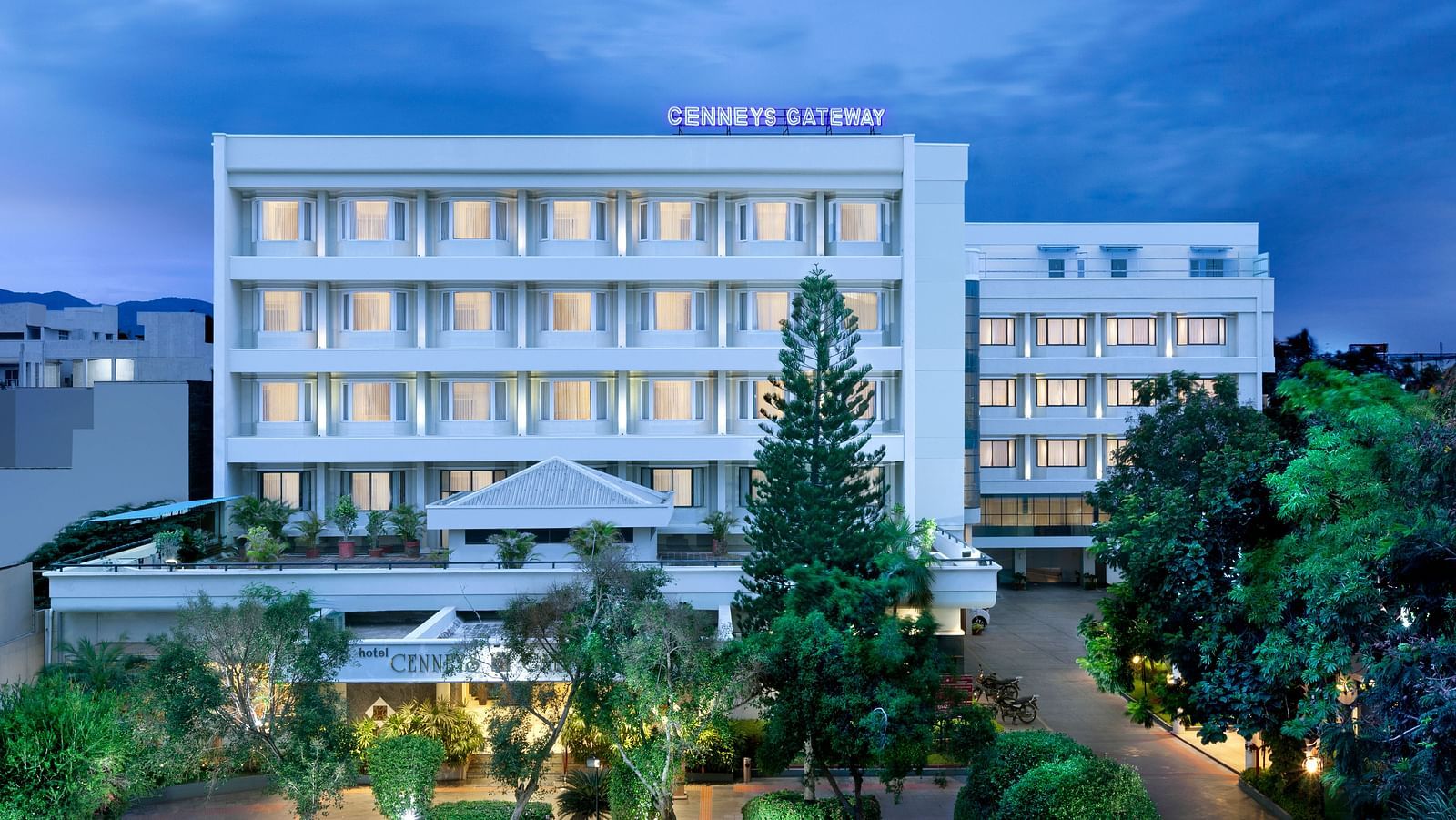 A facade view against the sky, surrounded by trees and plants in the front | Cenneys Gateway