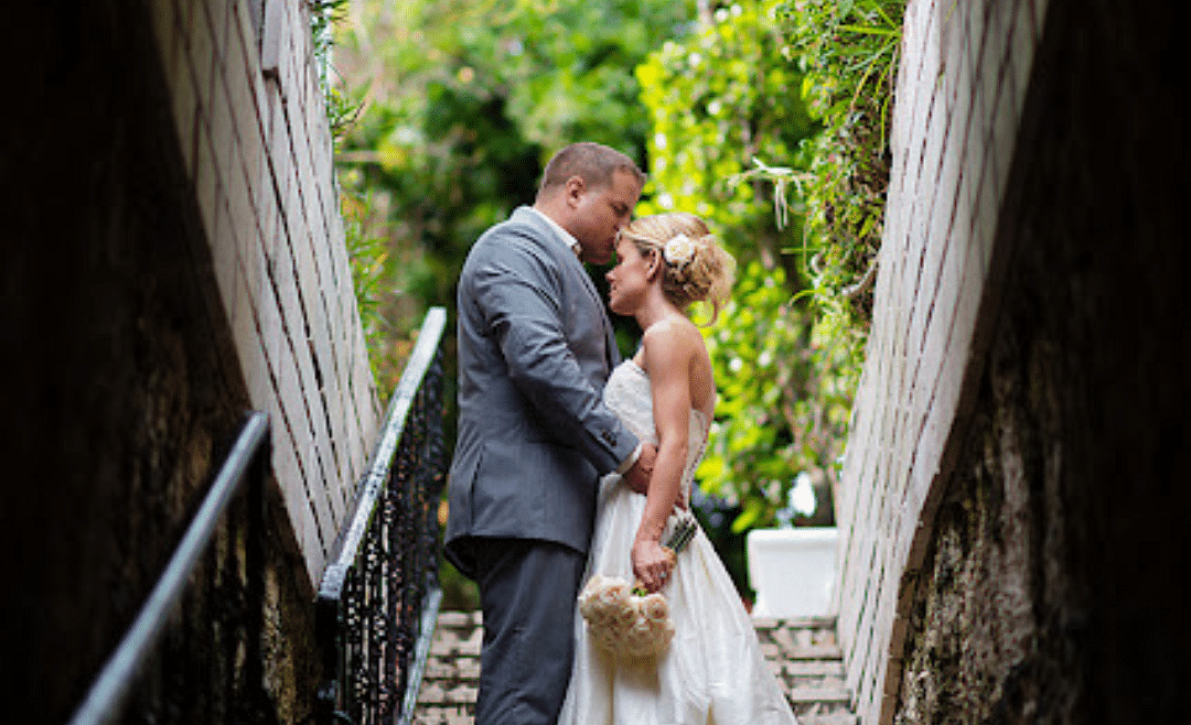 A couple standing in a narrow stone stairway tunnel, embracing each other under natural light | A Stone's Throw Away