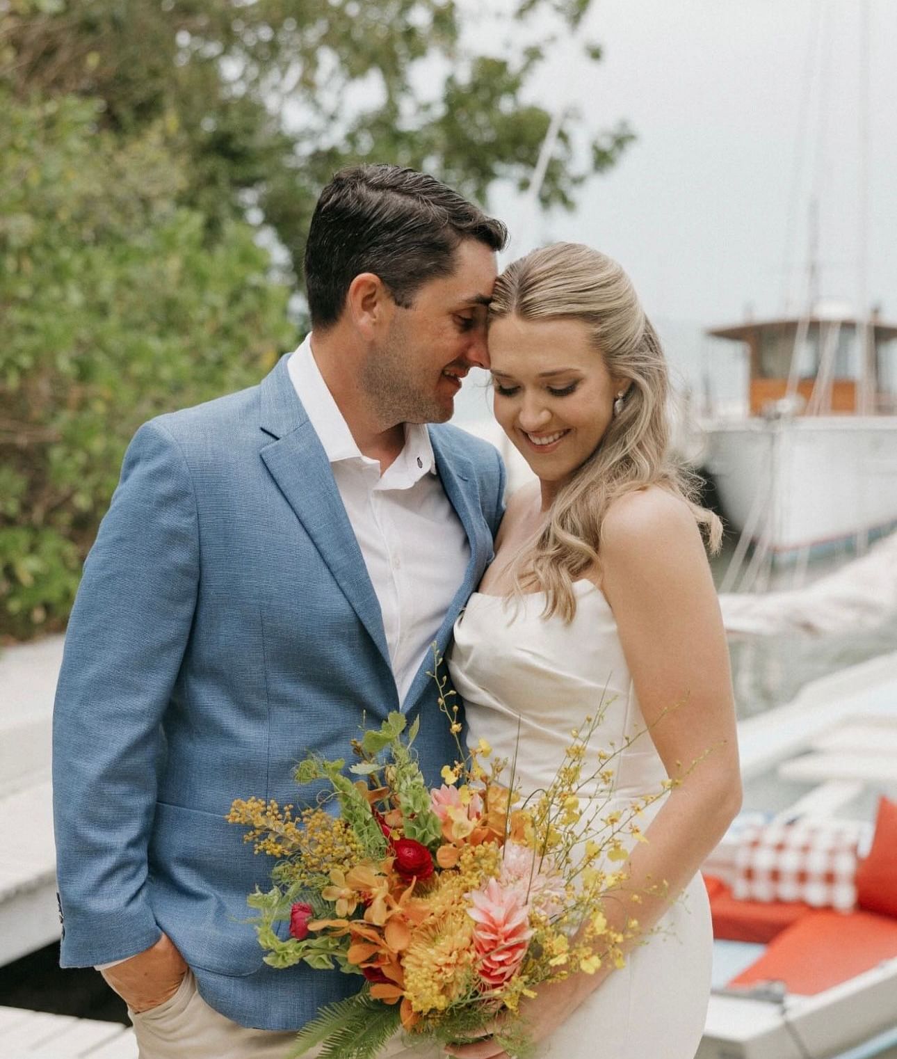 Bride and groom standing close, smiling and holding a vibrant bouquet of flowers at Casa Morada.