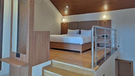 Bedroom with a double bed, wooden furnishings, loft area, and railing.