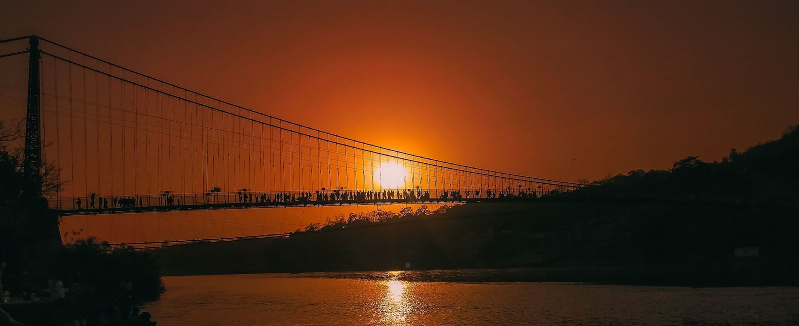 laxman jhula with people crossing the bridge during sunset
