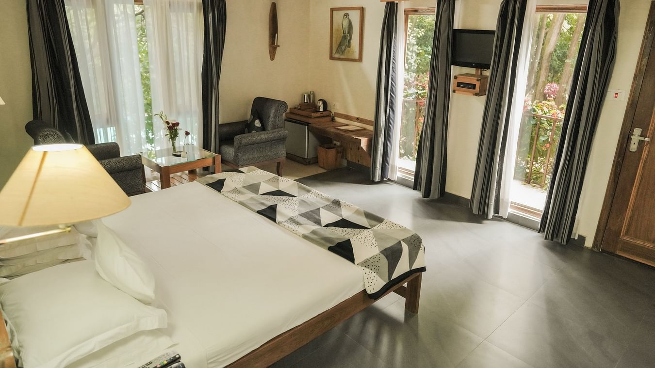 A living room with a couch, chairs, and a view of a garden - The Den Corbett Resort & Spa, Kumeria.