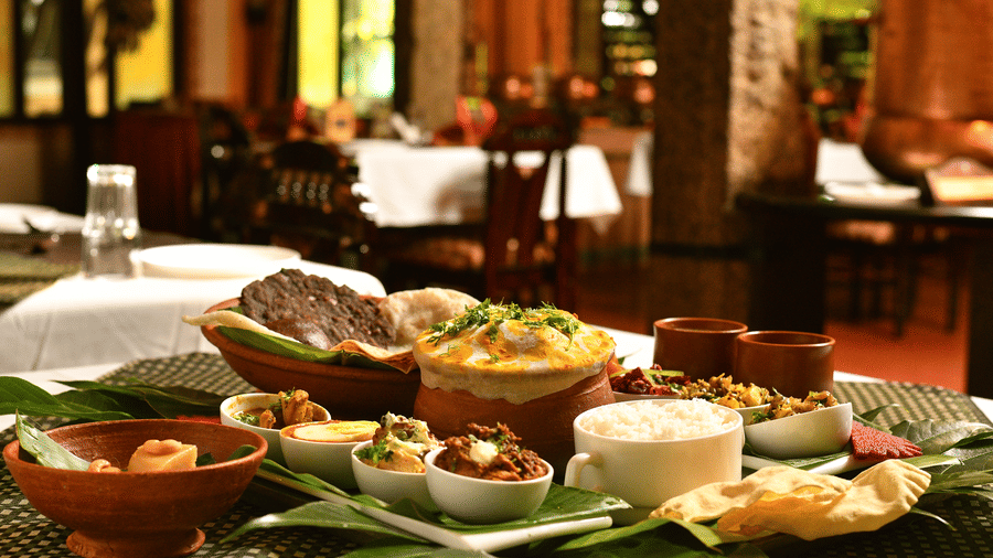A traditional spread of regional delicacies served on banana leaves, showcasing the best food in Hassan in a warm and inviting setting at Hoysala Village Resort.