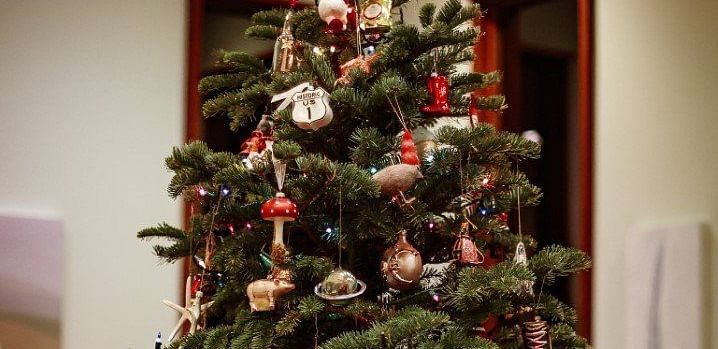A decorated Christmas tree with ornaments and lights, standing in a room with warm lighting.