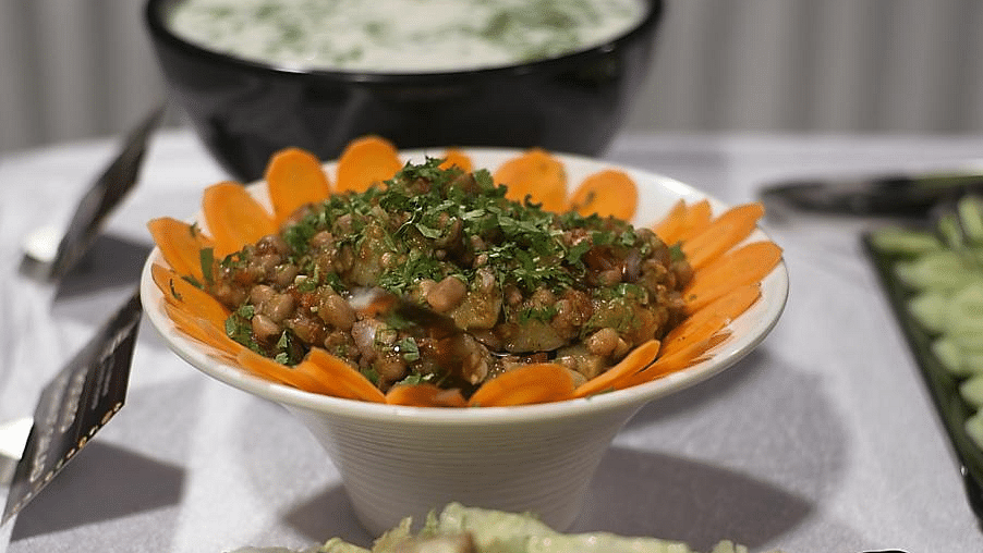Two bowls of salad, one white and one orange, on a table with a blurred background.