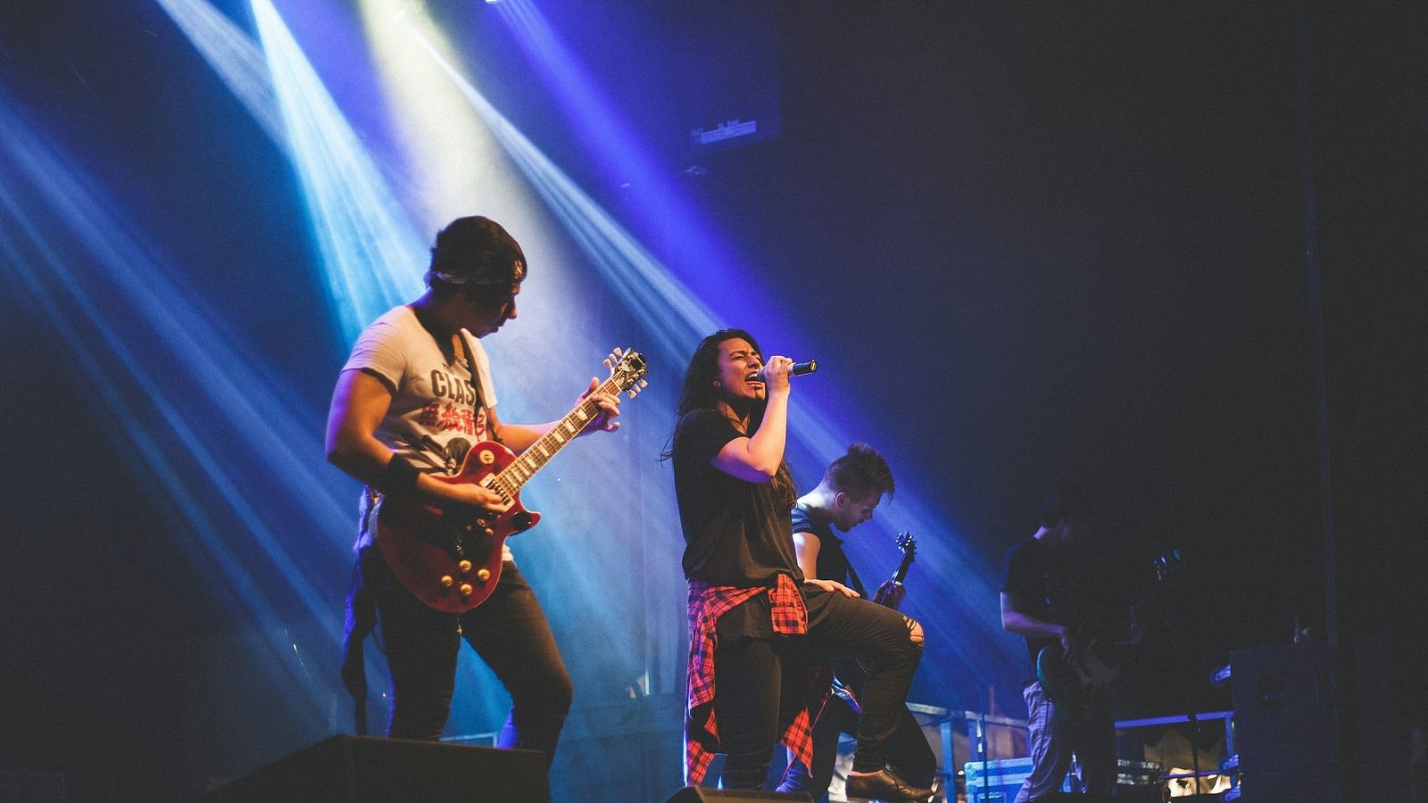 a band playing rock music on a stage with stage lights shining on them