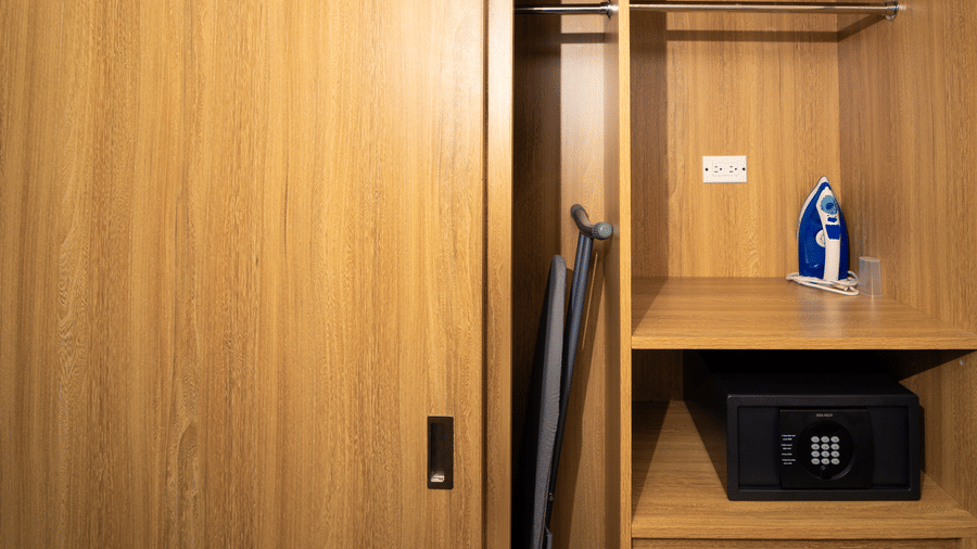 Wooden wardrobe with hanging space, an in-room safe, ironing board, and iron for added convenience during your Montego Bay stay | Hotel 39, Jamaica
