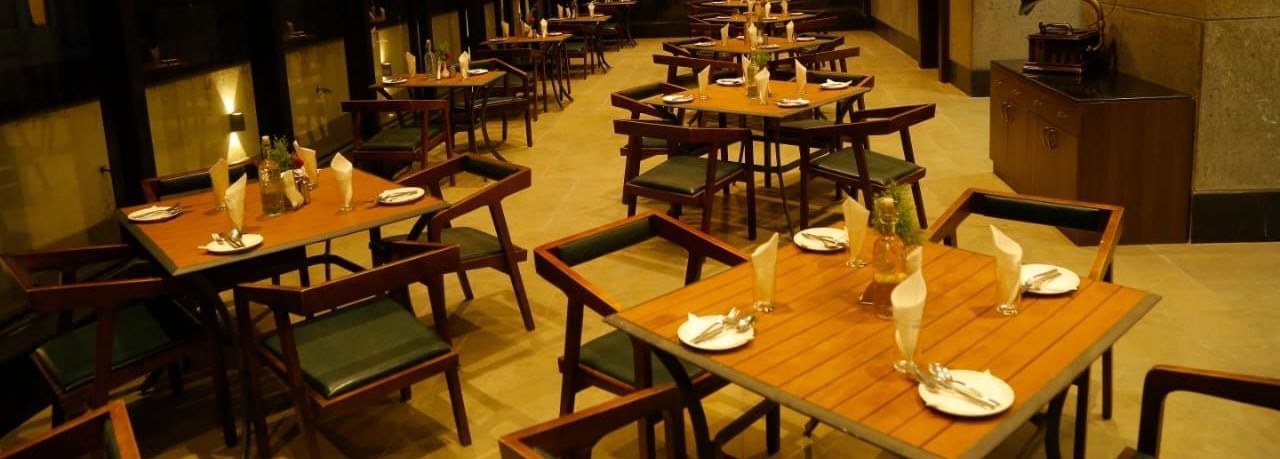 Spacious dining area with tables and chairs set for guests under warm lighting at The Hamuse Hotel, Kodaikanal.