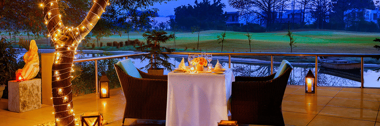 A romantic candlelight dinner set up next to a waterbody - Karma Lakelands.