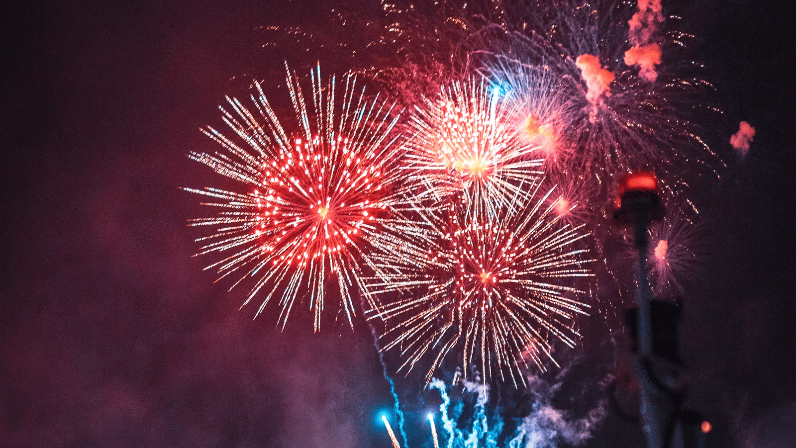 An overview of a lakeside venue with firecrackers in the sky that is illuminated on the waterbody during a New Year Party in Bangkok.