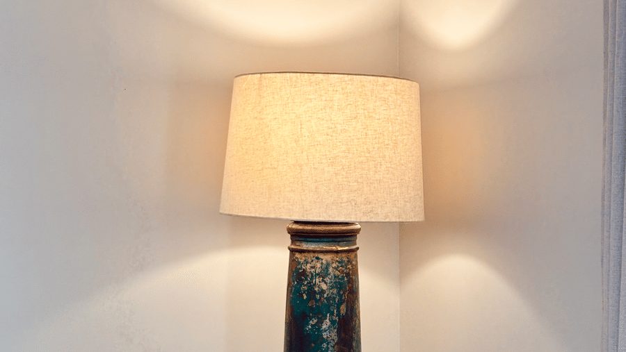 A corner of Vana Junior Suite featuring a tall lamp which is lit, making the corner illuminated.