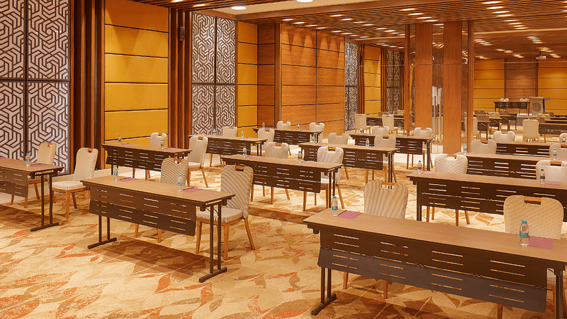 A close  side angle view of the Premier Banquet Hall at Residency Tower, Chennai, showcasing a royal interior design. The room features elegant decor with rich colors and intricate details. Classroom-style seating is arranged with tables and chairs, creati