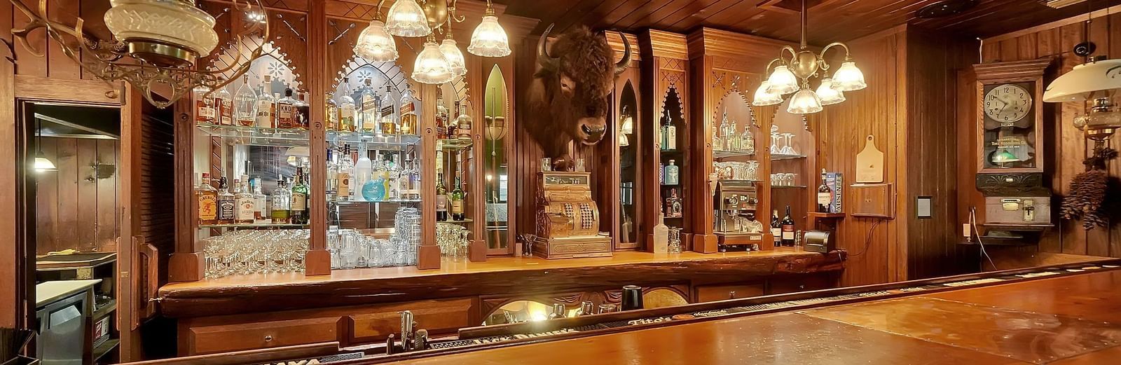 Buffalo Bar at Narrow Gauge Inn, with wooden interiors, bottles of alcohol placed on shelves, and rustic lighting.