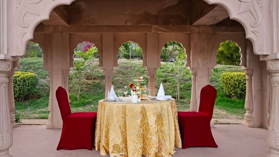 A table for two set up inside a canopy with lawn area in the background - Rajasthali Resort & Spa, Jaipur.