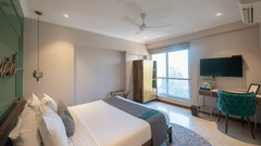 A bedroom with a view of the balcony, filled with natural light coming in through the window