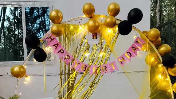 An outdoor event setup featuring a small round table covered with a  tablecloth and a large, colorful balloon arrangement in the background  at Coorg Orange Blossom Resort & Spa