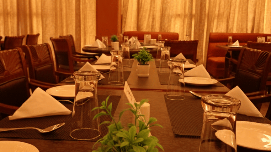 Table setup at Hotel Gold, Panipat with plates, glasses, cutlery, and decor arranged for dining.